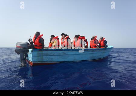 LAMPEDUSA, ITALIEN - SEPTEMBER 02: Flüchtlinge und Migranten warten darauf, von einem überfüllten kleinen Holzboot zu einem Irischen Kriegsschiff überführt zu werden, nachdem sie von Such- und Rettungscrew-Mitgliedern der deutschen NGO Sea-Eye etwa 46 Seemeilen (nm) von einem überfüllten kleinen Holzboot unterstützt und mit Rettungswesten und Trinkwasser versorgt wurden 2, 2017. Die Sicherheitslage für SAR-NGOs wie Sey-Eye hat sich verschlechtert, nachdem die so genannte libysche Kostengarde ihr Such- und Rettungsgebiet von 12nm auf 72nm erweitert hat. Gleichzeitig hat die Zahl der geretteten Menschen aus der Not von NGOs b Stockfoto