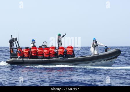 LAMPEDUSA, ITALIEN - SEPTEMBER 02: Flüchtlinge und Migranten werden gesehen, wie sie von einem überfüllten kleinen Holzboot zu einem irischen Kriegsschiff gebracht werden, nachdem sie von Such- und Rettungscrew-Mitgliedern der deutschen NGO Sea-Eye am 2. September 2017 von 46 Seemeilen (nm) mit Rettungswesten unterstützt und vorbereitet wurden. Die Sicherheitslage für SAR-NGOs wie Sey-Eye hat sich verschlechtert, nachdem die so genannte libysche Kostengarde ihr Such- und Rettungsgebiet von 12nm auf 72nm erweitert hat. Gleichzeitig ist die Zahl der geretteten Menschen aus der Not der NGOs zurückgegangen Stockfoto