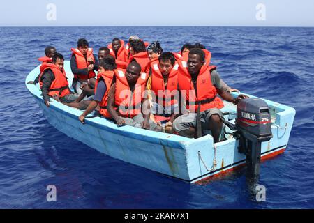 LAMPEDUSA, ITALIEN - SEPTEMBER 02: Flüchtlinge und Migranten warten darauf, von einem überfüllten kleinen Holzboot zu einem Irischen Kriegsschiff überführt zu werden, nachdem sie von Such- und Rettungscrew-Mitgliedern der deutschen NGO Sea-Eye etwa 46 Seemeilen (nm) von einem überfüllten kleinen Holzboot unterstützt und mit Rettungswesten und Trinkwasser versorgt wurden 2, 2017. Die Sicherheitslage für SAR-NGOs wie Sey-Eye hat sich verschlechtert, nachdem die so genannte libysche Kostengarde ihr Such- und Rettungsgebiet von 12nm auf 72nm erweitert hat. Gleichzeitig hat die Zahl der geretteten Menschen aus der Not von NGOs b Stockfoto