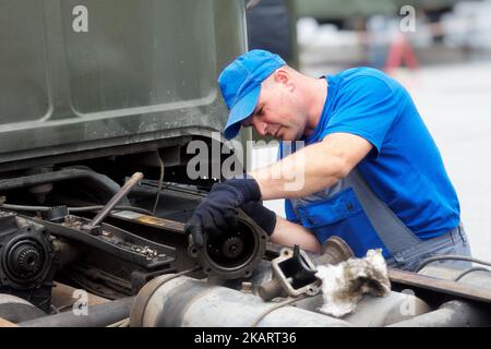 Mechaniker in Overalls repariert LKW am Sommertag draußen. Dringende Reparatur von LKWs. Authentischer Workflow... Stockfoto