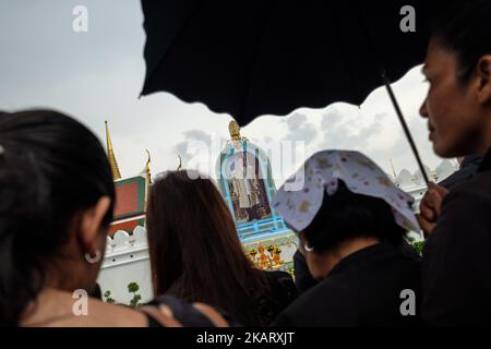 Am ersten Todestag von Thailands König Bhumibol Adulyadej stehen Tausende von thailändischen Trauernden vor den Toren des königlichen Palastes in Bangkok, um Blumen vor ein Bild des verstorbenen Königs zu legen und ihren Respekt zu zollen. (Foto von Thomas De Cian/NurPhoto) Stockfoto