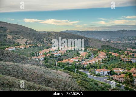 Blick auf eine reiche Nachbarschaft von einem Wanderweg in San Clemente, Kalifornien. Es gibt einen grünen Berghang an der Vorderseite mit Wohngebiet und einem Stockfoto