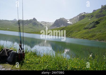 Angelruten und Angelausrüstung, die im Frühsommer am Ufer des Melchsees im Gras liegen. Stockfoto