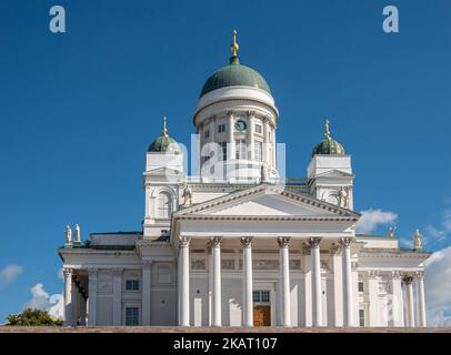 Helsinki, Finnland - 19. Juli 2022: Nahaufnahme der weißen Kathedrale vor blauem Himmel mit Kindern, mit Kuppel und Statuen Stockfoto