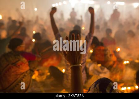 Hindu-Anhänger aus Bangladesch sitzen mit Kerzen und beten zu Gott im Shri Shri Lokanath 