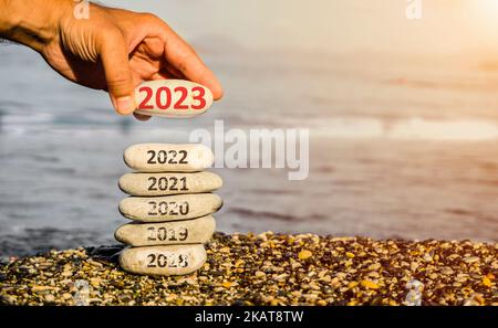 Frohes neues Jahr 2023 ersetzt alte 2022. Neues Jahr 2023 kommt Konzept Idee am Strand. Kreatives Fotobild kann als Banner, Social-Media-Beitrag verwendet werden. Stockfoto