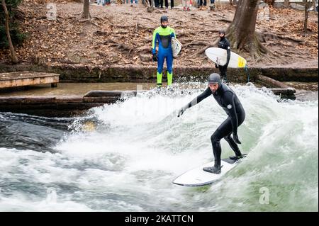 Ein Surfer am Eisbach (Eisstrom) im englischen Garten am 12.. Dezember 2017 in München. Die kälteste Luft der Saison konnte in München während des ganzen letzten Wochenendes spüren. In den Tagen vor dem Weihnachtstag war München, eine der wichtigsten Städte Deutschlands, voll mit Touristen, die den Schnee und die vielen Sehenswürdigkeiten der Stadt genossen. München, die Hauptstadt Bayerns und drittgrößte Stadt Deutschlands, liegt an der Isar am Rande der bayerischen Alpen. Im Mittelpunkt der historischen Münchner Innenstadt steht der große offene Platz, der Marienplatz, auf dem sich das Alte A befindet Stockfoto