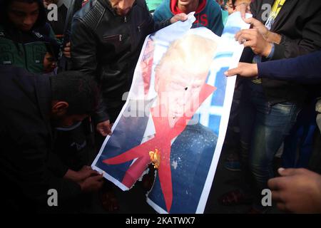 Palästinensische Demonstranten verbrennen ein Plakat, auf dem US-Präsident Donald Trump während eines Protestes gegen Trumps Entscheidung, Jerusalem in der Nähe des zentralen Gazastreifens als Hauptstadt Israels anzuerkennen, dargestellt wird. 15. Dezember 2017. (Foto von Majdi Fathi/NurPhoto) Stockfoto