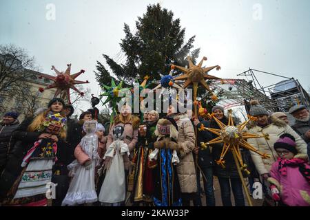 Eine Gruppe von Menschen posiert für ein Foto mit ihren Weihnachtssternen vor dem Weihnachtsbaum in der Nähe der Oper von Lemberg am Ende der Weihnachts-Stars-Parade, die am zweiten Weihnachtstag in Lemberg stattfand und vom Rynok-Platz aus läuft und vor der Svobody Avenue endet Des Opernhauses. Weihnachtssterne zu machen ist in der Ukraine eine alte Tradition. Der Sternehalter (zvizdar) ist die Person, die den Wertep führt und stolz den hellen handgefertigten Weihnachtsstern auf einem langen Pfahl hält. Der schönste und strahlendste Weihnachtsstern zu machen, hat sich in den letzten Jahren in der Westukraine zu einem echten Wettbewerb entwickelt. Stockfoto