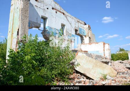 Eingestürzter mehrstöckiger Industriebau tagsüber. Katastrophenort voller Trümmer, zerbrochener Ziegelsteine und beschädigtem Haus ohne Wohngebäude. Konzept des Krieges AC Stockfoto