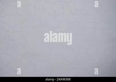 Gesprungener weißer alter Wandhintergrund. Horizontales Bild. Weiße schwarz graue Wand, Boden mit Rissen Textur Hintergrund Stockfoto