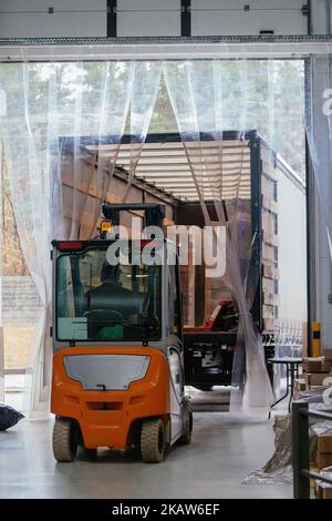 Der Gabelstaplerlader entlädt Ladung vom LKW Stockfoto