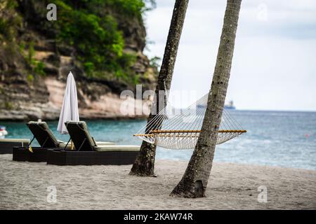 Ein schöner Blick auf Hängematte, Liegestühle und Sonnenschirm am Strand von St. Lucian vor dem Meer Stockfoto