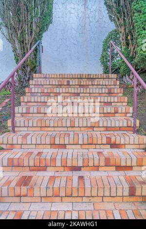 Außentreppe mit Ziegelsteinen und Eisengeländern führt zu einer strukturierten Wand in San Francisco, CA. Treppe mit hellorangefarbenen Ziegeln mit Blick auf zwei Tre Stockfoto