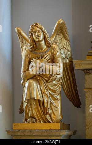 Helsinki, Finnland - 19. Juli 2022: Nahaufnahme der knieten goldenen Engelsstatue an der Seite des Hauptaltars in der Kathedrale. Stockfoto