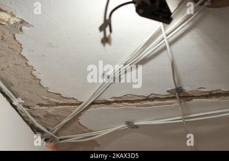 Befestigen der neuen Verkabelung an der Decke. Austausch und Verteilung der elektrischen Leitungen. Reparaturarbeiten in der Wohnung Stockfoto