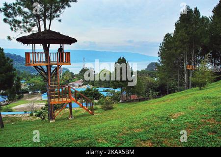 Ein Tourist schaut sich den Blick auf den Toba-See von der Spitze des Aussichtsturms an. Der Toba-See ist der größte vulkanische See in Südostasien. Der See liegt in Nord-Sumatra, Indonesien hat eine Länge von etwa 100 Kilometern, eine Breite von etwa 30 Kilometern und eine Tiefe von bis zu 505 Metern. In der Mitte dieses Sees befindet sich eine vulkanische Insel namens Samosir Island. Der Toba-See bildet sich schätzungsweise zum Zeitpunkt der Explosion vor etwa 73.000-75.000 Jahren und ist eine uralte Toba-Supervulkan-Eruption. Derzeit Lake Toba wurde zu einem der beliebtesten touristischen Destinationen der lokalen und ausländischen Touristen Stockfoto