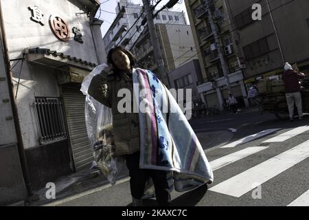 OSAKA, JAPAN - 31. MÄRZ: Eine obdachlose Frau geht am 31. März 2018 auf der Straße von Airin in der Nishinari Station in einem Gebiet, in dem eine der größten Obdachlosen- und Tagelöhnerpopulationen des Landes in der Präfektur Osaka, Japan, lebt. Japan, die drittgrößte Volkswirtschaft der Welt, war einst stolz darauf, eine allgemein bürgerliche Gesellschaft zu sein und frei von der Armut mit den übrigen reichen Ländern zu sein, aber Tausende versuchten, auf der Straße zu leben, um mit dem Zusammenbruch der Blasenwirtschaft im Jahr 1990s „Homuresu“ zu werden. Dies hat Japans Versprechen, lebenslange, sichere Arbeitsplätze für alle Männer in Unternehmen zu schaffen, zunichte gemacht. Jap Stockfoto