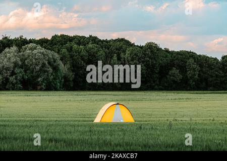 Ein digitales 3D Rendering eines gelben Campingzelts in einem ländlichen Tal in der Nähe von grünen Bäumen Stockfoto