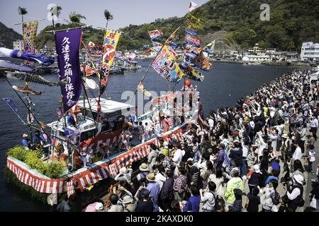 Eine Schiffsladung tanzender Fischer mit ihren weißen Gesichtern, die mit Frauenroben gekleidet waren, stand während des Ose Matiri/Festivals im Osezaki-Bezirk Numazu, Präfektur Shizuoka in Japan am 4. April 2018 im Mittelpunkt des Fischerhafens von Uchiura. Die festlichen Boote, die mit bunten Fahnen geschmückt waren, zogen den Hafen nach dem Weg zu einem nahe gelegenen Ose Jinja-Schrein, wo die Fischer Gebete für einen großen Fang und sicheres Segeln anboten. Die Fischer verkleiden sich traditionell während des Festes als Frauen, um sichere Ausflüge ins Meer und gute Fänge zu gewährleisten. Der Brauch soll von einer lokalen Folklore stammen Stockfoto