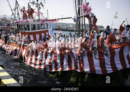 Eine Schiffsladung tanzender Fischer mit ihren weißen Gesichtern, die mit Frauenroben gekleidet waren, stand während des Ose Matiri/Festivals im Osezaki-Bezirk Numazu, Präfektur Shizuoka in Japan am 4. April 2018 im Mittelpunkt des Fischerhafens von Uchiura. Die festlichen Boote, die mit bunten Fahnen geschmückt waren, zogen den Hafen nach dem Weg zu einem nahe gelegenen Ose Jinja-Schrein, wo die Fischer Gebete für einen großen Fang und sicheres Segeln anboten. Die Fischer verkleiden sich traditionell während des Festes als Frauen, um sichere Ausflüge ins Meer und gute Fänge zu gewährleisten. Der Brauch soll von einer lokalen Folklore stammen Stockfoto