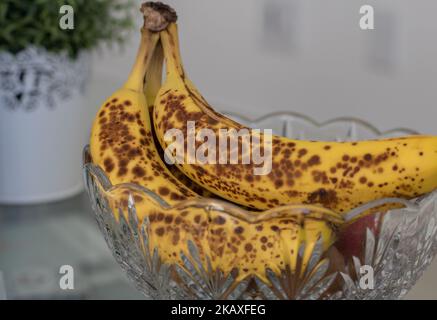 Nahaufnahme vollreifer Bananen, die auf eine Obstschale gelegt werden Stockfoto