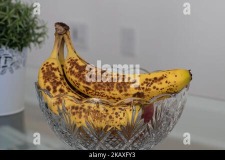 Nahaufnahme vollreifer Bananen, die auf eine Obstschale gelegt werden Stockfoto