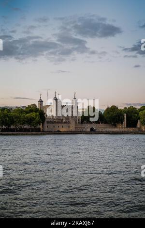 Der Tower of London, der im Sonnenlicht von Bäumen umgeben ist, liegt auf der Nordseite des Weltkulturerbes der Themse, der einst im Königspalast die Kronjuwelen hielt. Stockfoto