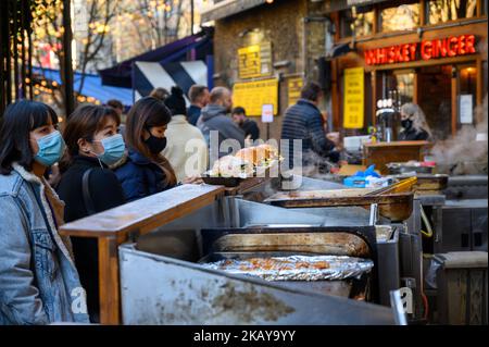 LONDON - 4. November 2020: Menschen tragen PPE-Gesichtsmasken und bestellen Burger an einem Street-Food-Stand im Borough Market Stockfoto