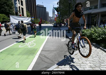 Ein Radfahrer springt, während er am 30. Juni 2018 einen protestmarsch durch Center City in Philadelphia, PA, passiert. Tausende nehmen früher an einer Kundgebung Teil, um gegen die Einwanderungspolitik der Trump-Regierung zu protestieren, und ähnliche Ereignisse finden im ganzen Land statt. (Foto von Bastiaan Slabbers/NurPhoto) Stockfoto