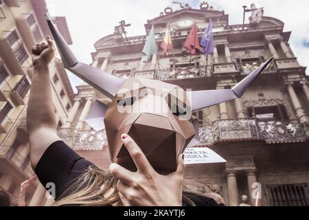 Der Aktivist gegen Tierquälerei bei Stierkämpfen trägt vor den Feierlichkeiten in San Fermin, Spanien, eine Papptafel-Bullkopfmaske unter dem stadtratsgebäude von Pamplona. (Foto von Celestino Arce/NurPhoto) Stockfoto