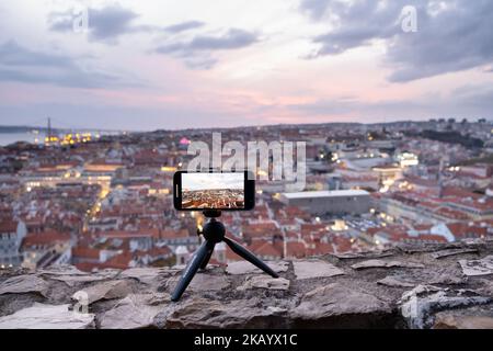 Ein Tourist schießt den Blick von Castelo de S. Jorge (Burg) auf einem iphone, wenn es in Lissabon, Portugal, im März 2022, Nacht wird. Bildnachweis: Rob Watkins Stockfoto