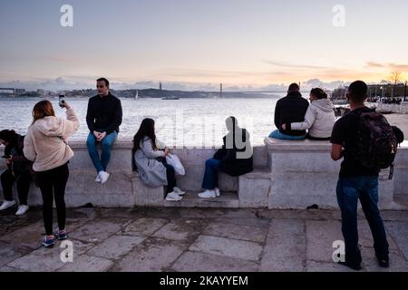 IDYLLISCHER ABEND: Touristen genießen den Blick auf die Brücke Ponte 25 de Abril und Santuário de Cristo Rei an der Promenade Tejo, Fluss Tejo (Rio Tejo), Lissabon Stockfoto