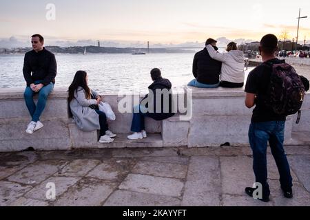 IDYLLISCHER ABEND: Touristen genießen den Blick auf die Brücke Ponte 25 de Abril und Santuário de Cristo Rei an der Promenade Tejo, Fluss Tejo (Rio Tejo), Lissabon Stockfoto