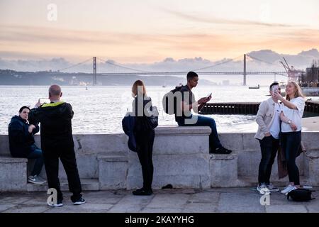 IDYLLISCHER ABEND: Touristen genießen den Blick auf die Brücke Ponte 25 de Abril und Santuário de Cristo Rei an der Promenade Tejo, Fluss Tejo (Rio Tejo), Lissabon Stockfoto