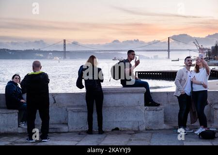 IDYLLISCHER ABEND: Touristen genießen den Blick auf die Brücke Ponte 25 de Abril und Santuário de Cristo Rei an der Promenade Tejo, Fluss Tejo (Rio Tejo), Lissabon Stockfoto