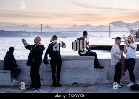 IDYLLISCHER ABEND: Touristen genießen den Blick auf die Brücke Ponte 25 de Abril und Santuário de Cristo Rei an der Promenade Tejo, Fluss Tejo (Rio Tejo), Lissabon Stockfoto