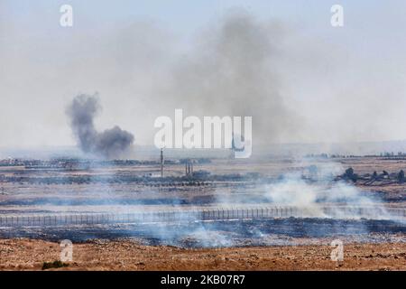 Auf der israelischen Seite des Grenzzauns zwischen Israel und Syrien auf den Golanhöhen brennt ein Brushfeuer, während am Freitag, dem 27. Juli 2018, unmittelbar hinter dem Grenzzaun in Syrien zwischen syrischen Regierungskräften und IS-Kämpfern Kämpfe wüten. (Foto von Mati Milstein/NurPhoto) (Foto von Mati Milstein/NurPhoto) Stockfoto