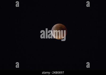 Der „Blutmond“ vor und während der Mondfinsternis im verwüsteten, aus dem Feuer stammenden Gebiet namens Mati in der Nähe von Athen. Das Schiff gehört der Küstenwache, da sie immer noch nach Menschen suchen. Die Finsternis ist die längste totale Mondfinsternis des Jahrhunderts, die einen Blutmond während eines Vollmondes zeigt 27. Juli 2018 - Mati, Attica - Griechenland (Foto von Nicolas Economou/NurPhoto) Stockfoto