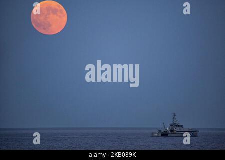 Der „Blutmond“ vor und während der Mondfinsternis im verwüsteten, aus dem Feuer stammenden Gebiet namens Mati in der Nähe von Athen. Das Schiff gehört der Küstenwache, da sie immer noch nach Menschen suchen. Die Finsternis ist die längste totale Mondfinsternis des Jahrhunderts, die einen Blutmond während eines Vollmondes zeigt 27. Juli 2018 - Mati, Attica - Griechenland (Foto von Nicolas Economou/NurPhoto) Stockfoto