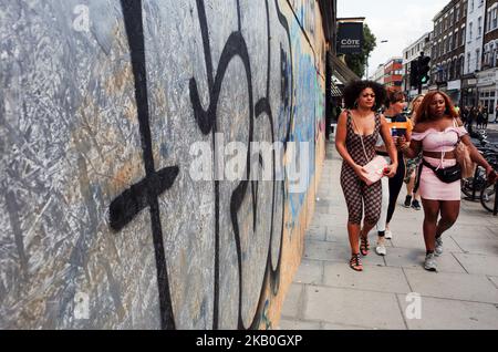 Zwei Frauen passieren ein aufgetretene Schaufenster, während Feiernden und Paraderinnen die Straßen von Notting Hill im Westen Londons für den Haupttag des Notting Hill Carnival 2018 in London, England, am 27. August 2018 packen. Es werden Hunderttausende erwartet, wobei die Metropolitan Police inzwischen in Kraft getreten ist, um dem Ruf des Karnevals als Hotspot für Kriminalität und Bandengewalt entgegenzuwirken. (Foto von David Cliff/NurPhoto) Stockfoto