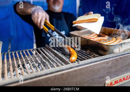 Koch kocht Würstchen, Hotdogs auf dem Grill, Grill, rollende Hand wartet auf Hot Dog Wurst Stockfoto