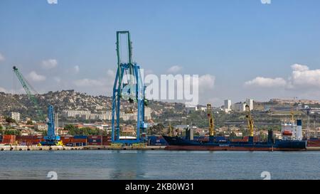 MARSEILLE, FRANKREICH - 18. MAI 2018: Containerschiff und Krane im Handelsdock mit der Stadt im Hintergrund Stockfoto