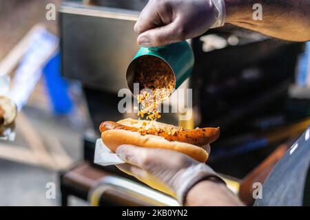 Nahaufnahme des Küchenchefs, der eine Wurst in einer Rolle hält, Hot Dog mit Löwen, die umgezogen werden, Street Food, Mittagessen, Snack, Stockfoto