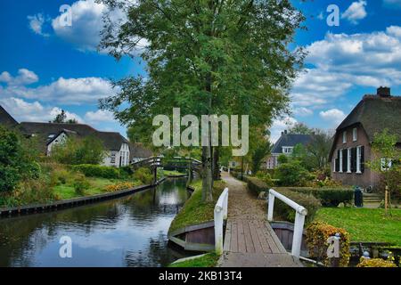 Das malerische holländische Dorf Giethoorn, mit einem Kanal, engen Holzbrücken, Bäumen und reetgedeckten alten Bauernhäusern. Stockfoto