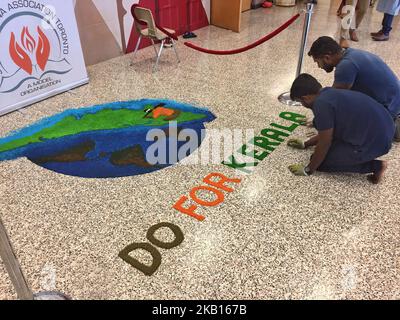 Jugendliche schaffen einen farbenfrohen Rrangoli (Rrangoli, auch bekannt als kolam, ist ein traditionelles Design, das mit farbigem Pulver auf den Boden gezogen wurde) mit den Worten „Do for Kerala“, da Mitglieder der kanadischen Malayalee-Gemeinschaft an einer Spendenaktion für die Opfer der Überschwemmungen in Kerala teilnehmen, Indien. Die Spendenaktion fand am 15. September 2018 in Mississauga, Ontario, Kanada, statt und Hunderte kamen, um ihre Unterstützung zu geben. Durch heftige Regenfälle wurden mehr als 800.000 Menschen vertrieben und mehr als 373 Menschen bei der so genannten schlimmsten Überschwemmung in Kerala seit fast einem Jahrhundert getötet. Alle 14 Bezirke der St Stockfoto