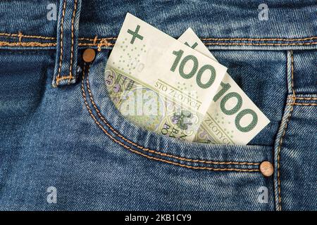 100 Zloty-Banknoten in der Jeanstasche. Geld in der Vordertasche der Jeans. Das Konzept von Investitionen, Bargeld, Vermögen und Gewinn, Urheberrecht. Stockfoto