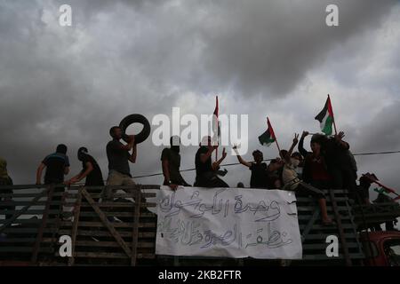 Palästinensische Demonstranten fahren in einem Lastwagen mit palästinensischen Flaggen, während sie während der Zusammenstöße entlang der Grenze mit Israel östlich von Gaza-Stadt am 26. Oktober 2018 Reifen mitbringen, die zur Deckung verbrannt werden sollen. (Foto von Majdi Fathi/NurPhoto) Stockfoto