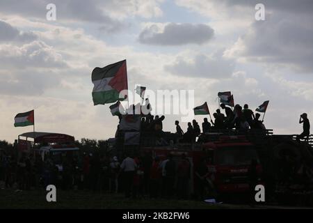 Palästinensische Demonstranten fahren in einem Lastwagen mit palästinensischen Flaggen, während sie während der Zusammenstöße entlang der Grenze mit Israel östlich von Gaza-Stadt am 26. Oktober 2018 Reifen mitbringen, die zur Deckung verbrannt werden sollen. (Foto von Majdi Fathi/NurPhoto) Stockfoto