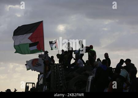 Palästinensische Demonstranten fahren in einem Lastwagen mit palästinensischen Flaggen, während sie während der Zusammenstöße entlang der Grenze mit Israel östlich von Gaza-Stadt am 26. Oktober 2018 Reifen mitbringen, die zur Deckung verbrannt werden sollen. (Foto von Majdi Fathi/NurPhoto) Stockfoto